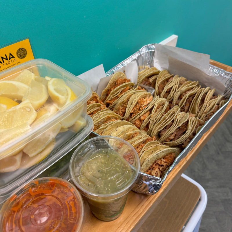 Tray of food items including tortillas, guacamole, and sour cream on a blue surface.
